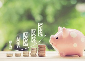 Piggy bank next to an increasingly tall stack of coins