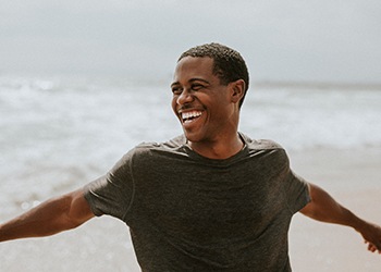 a man smiling and walking on a beach