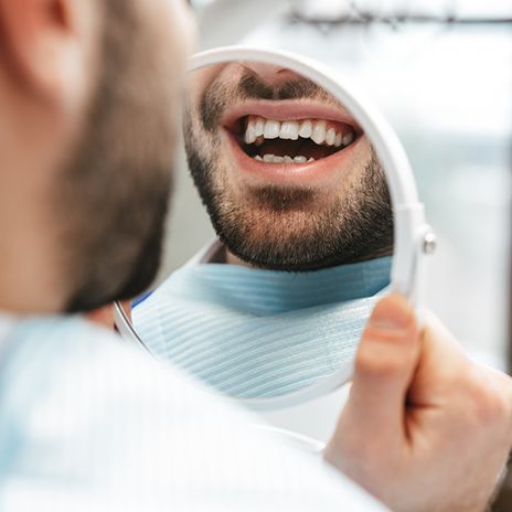 a man looking at his teeth in a mirror