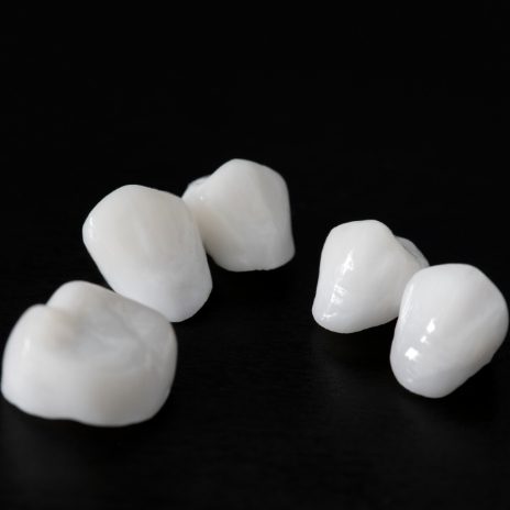 Five white dental crowns against black background