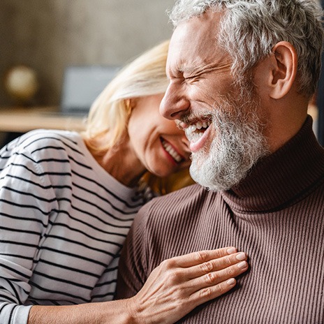 couple sitting on the couch laughing and smiling 