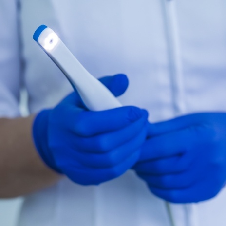 Dental professional holding a thin white intraoral camera