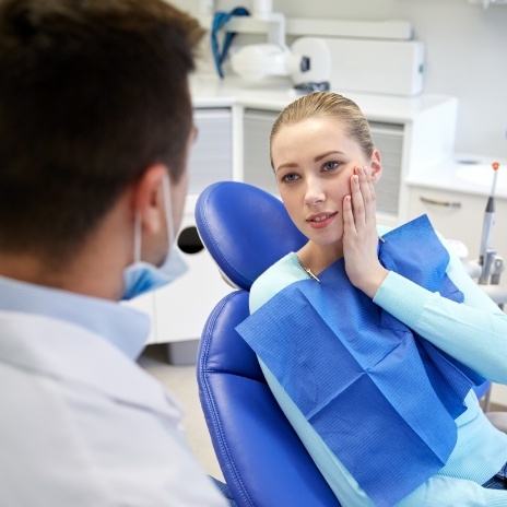 Woman holding her cheek in pain while talking to emergency dentist in Alpharetta