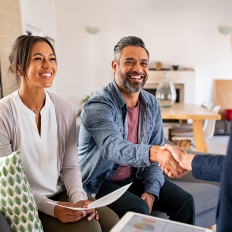 Smiling man shaking hands with someone sitting across from him