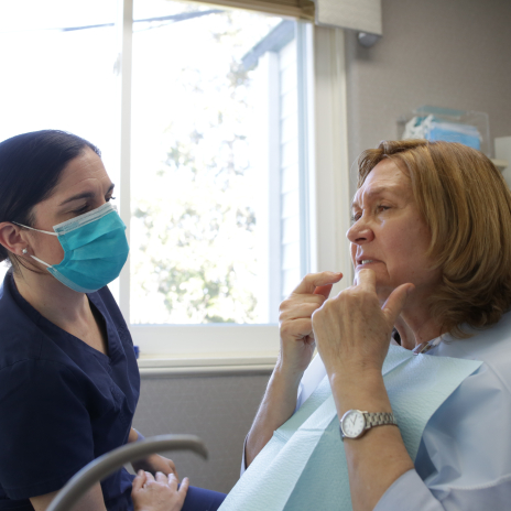 Woman in dental chair pointing to her mouth
