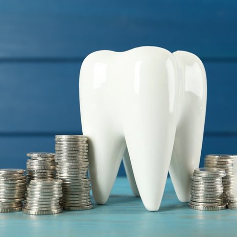 a model of a tooth next to a stack of coins