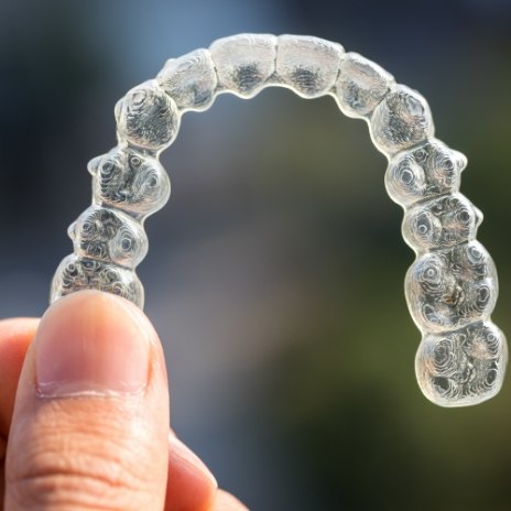 Hand holding a SureSmile clear aligner in Alpharetta