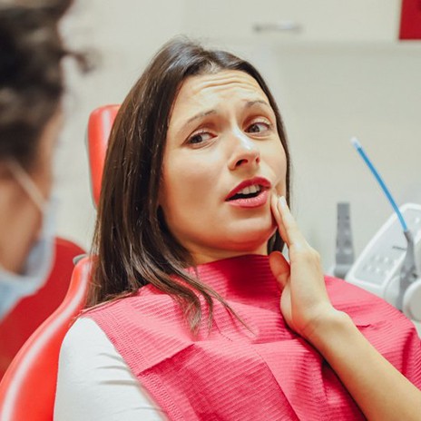 Patient rubbing jaw and explaining symptoms to dentist